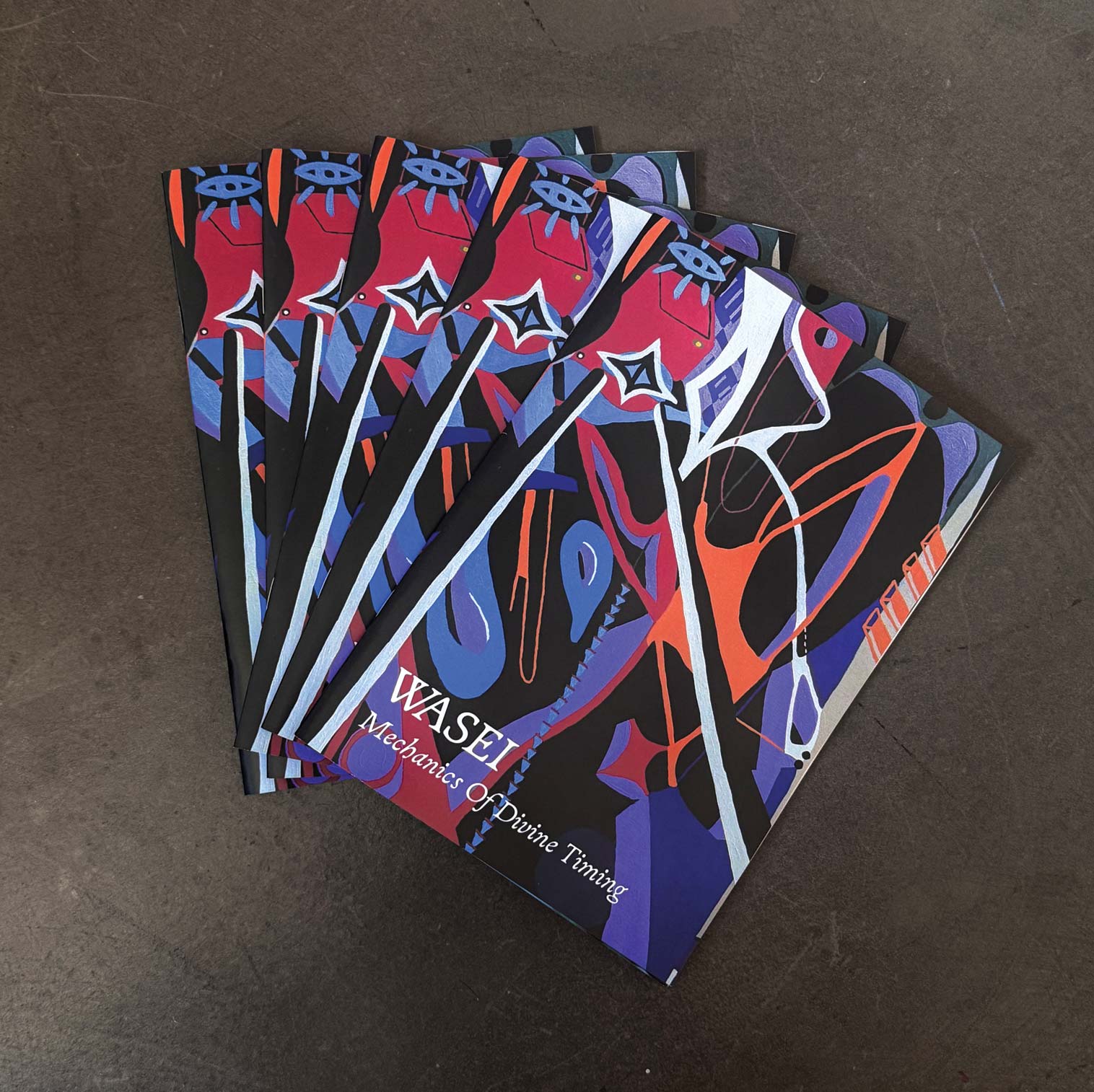 Five copies of WASEI's Mechanics of Divine Timing spread on a concrete floor